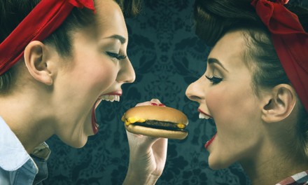 Zwei Frauen essen einen Burger Zwei Frauen essen einen Burger