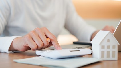 Nahaufnahme eines Mannes, der etwas in einen Taschenrechner tippt, um die Miete zu berechnen