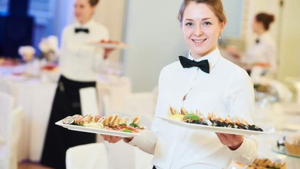 Kellnerin trägt zwei Teller mit Speisen