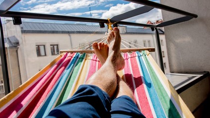 Mann liegt in einer Hängematte auf dem Balkon