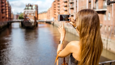 Frau fotografiert mit ihrem Smartphone die Speicherstadt