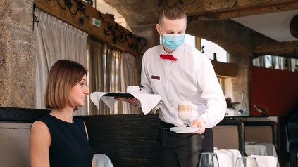 Kellner mit Schutzmaske serviert einen Kaffee