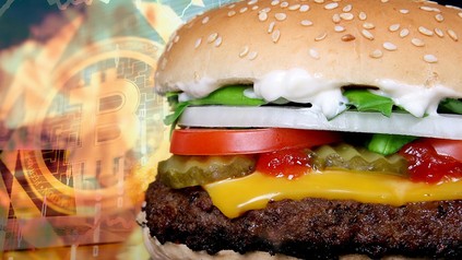 Eine Bitcion-Münze neben einem Whopper