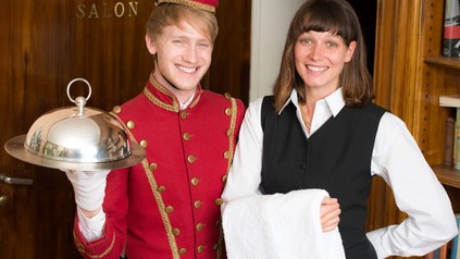 Zwei fröhliche Auszubildende in der Hotellerie bei der Arbeit