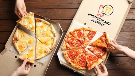 Nahaufnahme von zwei geöffneten Pizzakartons, aus denen sich vier Hände Pizzastücke nehmen