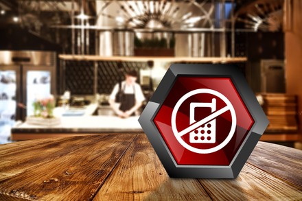 Ein Verbotsschild für Handys auf einem Restauranttisch