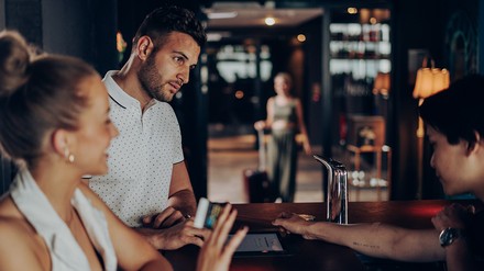 Mann und Frau stehen an einer Rezeption