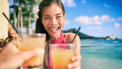 Eine Urlauberin mit einem Cocktail in der Hand