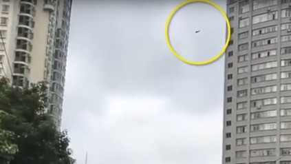 Mann seilt sich an Telefonkabel von Hochhaus