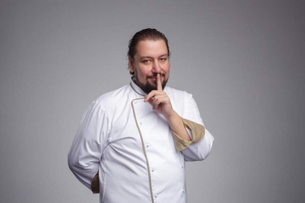 Koch hält sich Zeigefinger an den Mund