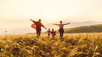 Vater, Mutter und zwei Kinder, die dem Sonnenuntergang entgegen laufen