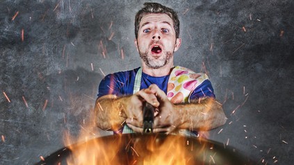 Koch sieht aufgeregt auf seine brennende Pfanne