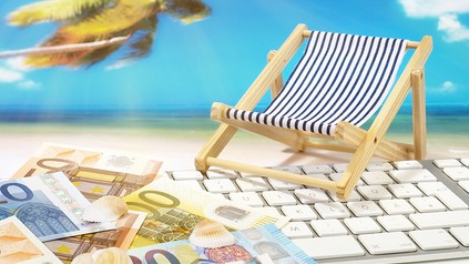 Ein Liegestuhl und Geld auf einer Computertastatur