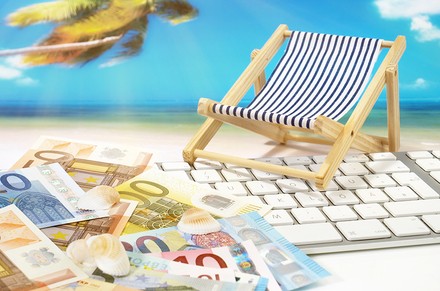 Ein Liegestuhl und Geld auf einer Computertastatur