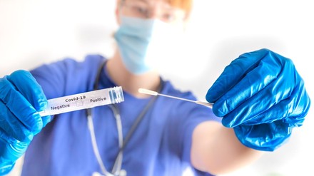 eine Ärztin hält ein Abstrichröhrchen mit Coronavirus in der Hand