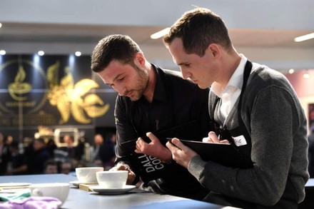 Zwei Männer betrachten eine Tasse Kaffee