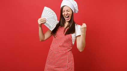 Eine Köchin mit einem Bündel Geldscheine in der Hand