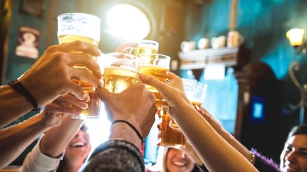 Eine Gruppe von Leute stoßt in einer Bar mit Bier an