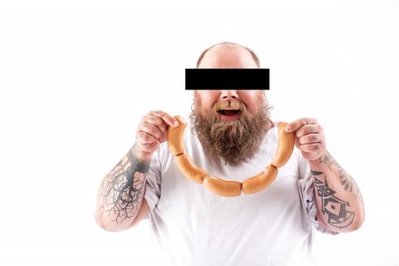 Mann mit Bart hält Wurst in Händen, das Gesicht ist zensiert