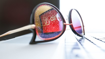 Eine Brille, in der sich das Airbnb-Logo spiegelt