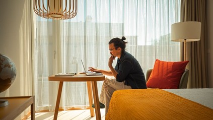 Mann arbeitet in einem Hotelzimmer am Laptop