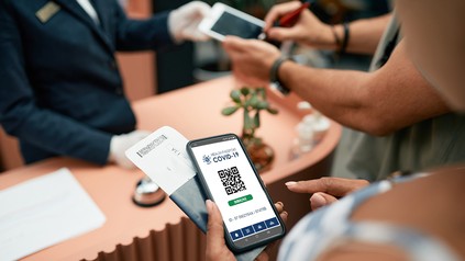 Frau hält für den Check-in im Hotel ihren Impfnachweis bereit