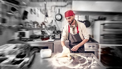 Ein Koch knetet Teig in einer Küche