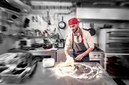 Ein Koch knetet Teig in einer Küche