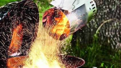 Glühende Kohlen werden in einen Griller geschüttet