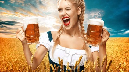 Frau hält zwei Bierkrüge in der Hand und zwinkert in die Kamera