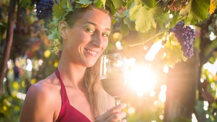 Frau hält Rotwein in der Hand und lächelt