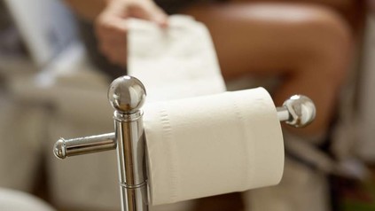 Person reißt Toilettenpapier ab