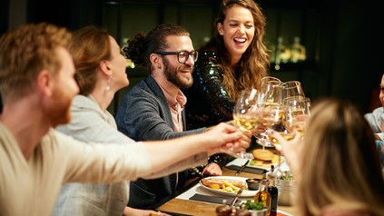 Gruppe von Freunden, die gemeinsam beim Essen im Restaurant anstoßen