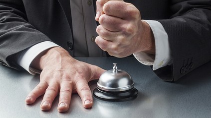 Eine Faust, die auf eine Rezeptionsklingel im Hotel schlägt