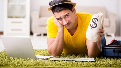 Mann mit Geldsack in der Hand sitzt verzweifelt vor Laptop