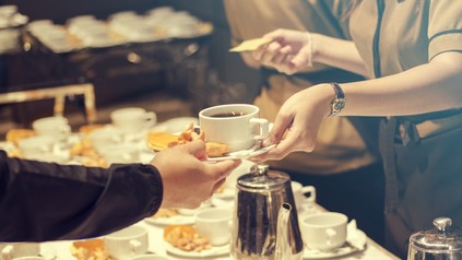 Servicekraft reicht Mann eine Tasse Kaffee