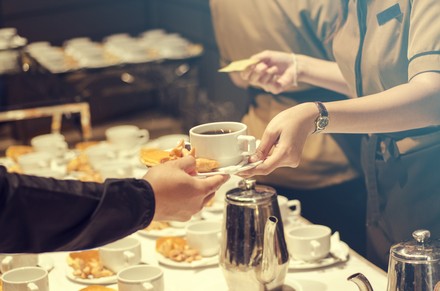Servicekraft reicht Mann eine Tasse Kaffee