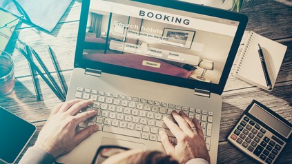 Mann sitzt vor Laptop und bucht Reise