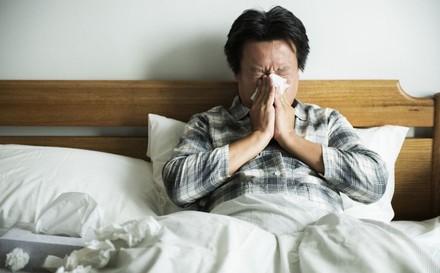 Erkälteter Mann liegt im Bett