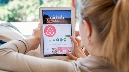 Junge Frau installiert die Airbnb-App auf dem Tablet