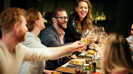 Freunde sitzen gemütlich im Restaurant zusammen und stoßen an