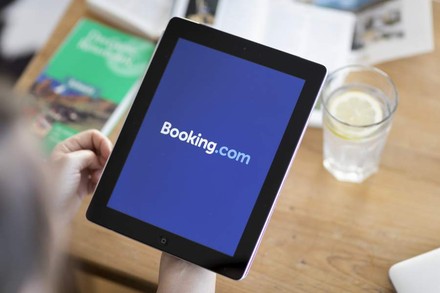 Eine Person hält ein Tablet auf dem die Booking.com App aufgerufen ist
