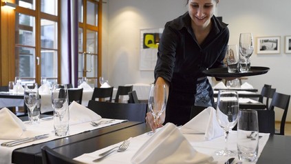 Kellnerin deckt einen Tisch ein