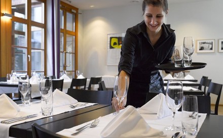 Kellnerin deckt einen Tisch ein