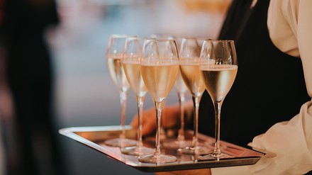 Kellnerin trägt ein Tablett mit gefüllten Sekt- oder Champagnergläsern