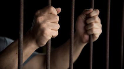 Zwei Hände greifen Gitterstäbe