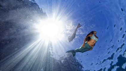 Zwei Frauen in Meerjungfrauenkostümen tauchen unter Wasser