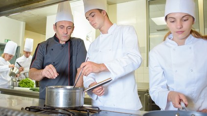 Koch arbeitet mit Lehrlingen