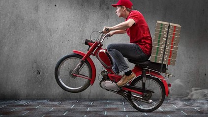 Ein Mann auf einem Mofa und Pizzakartons auf dem Gepäckträger fährt los