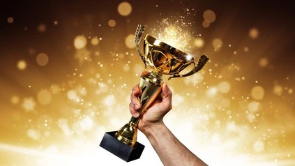 Eine Hand hält einen goldenen Pokal hoch